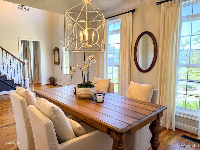 dining area featuring hardwood / wood-style flooring, ornamental molding, and an inviting chandelier