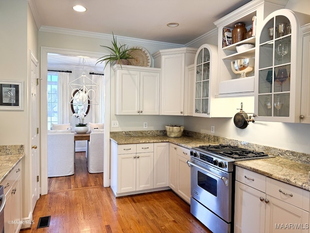 kitchen with high end range, light stone counters, crown molding, hardwood / wood-style floors, and white cabinets