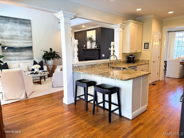 kitchen with white cabinets, light stone countertops, kitchen peninsula, and sink