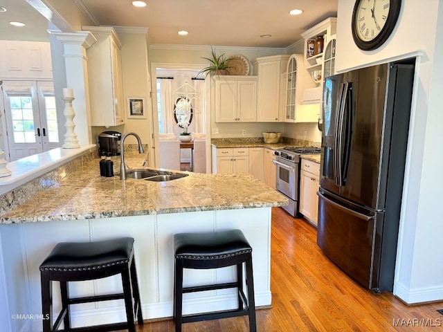 kitchen featuring light stone countertops, a sink, black fridge with ice dispenser, high end stainless steel range, and a peninsula