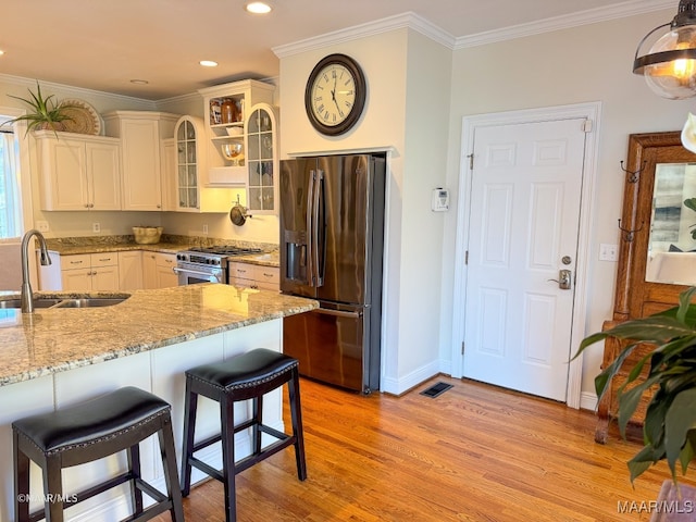 kitchen with light stone countertops, a kitchen breakfast bar, stainless steel appliances, sink, and pendant lighting