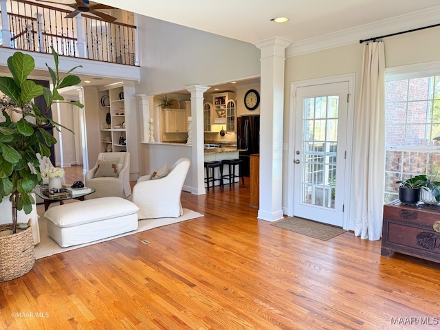 living room with decorative columns, ceiling fan, ornamental molding, and hardwood / wood-style flooring