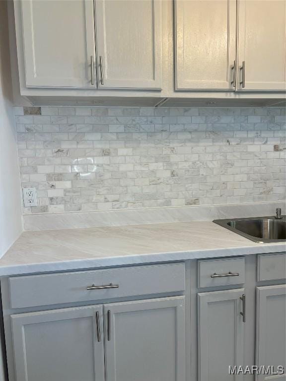 kitchen with decorative backsplash, gray cabinets, and light stone counters