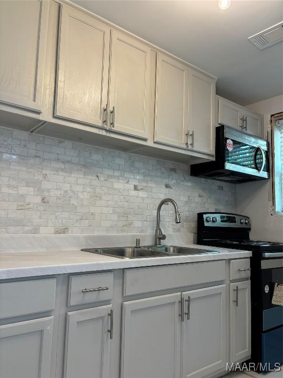 kitchen with decorative backsplash, white cabinets, black / electric stove, and sink