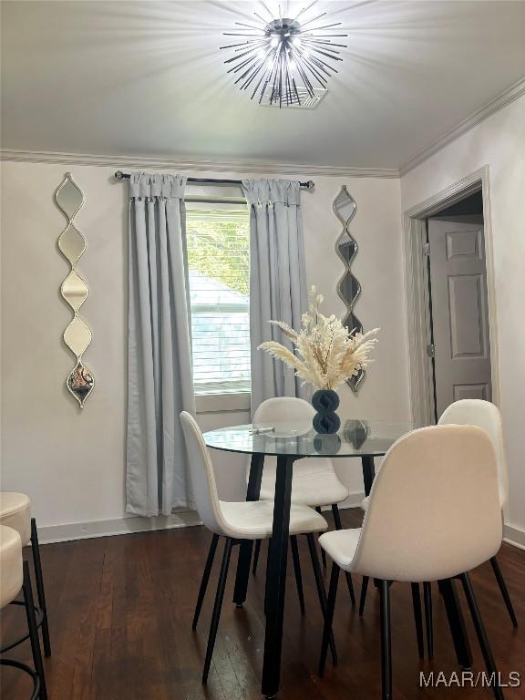 dining room featuring dark hardwood / wood-style flooring, an inviting chandelier, and ornamental molding