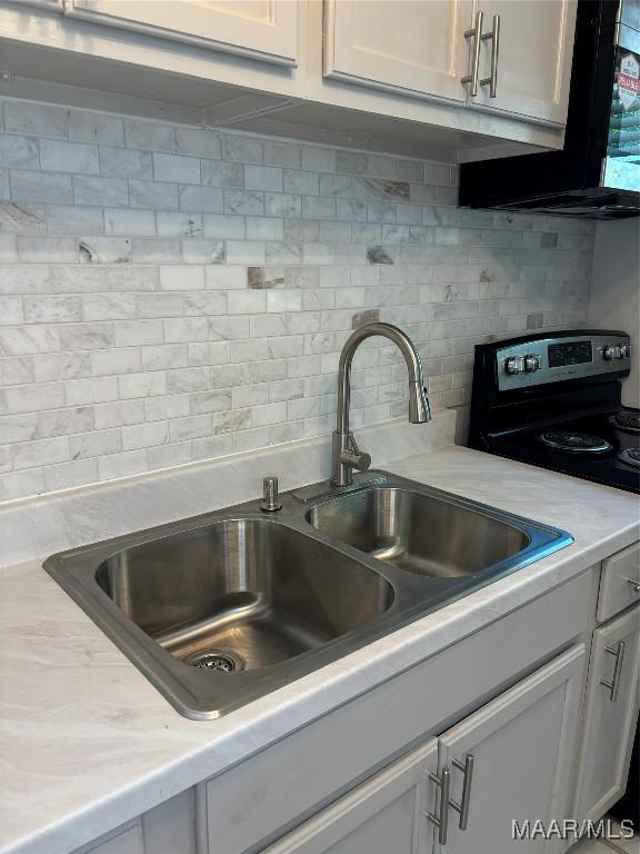 kitchen with white cabinetry, backsplash, electric range, and sink