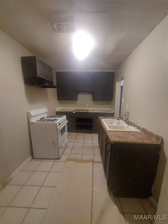 kitchen with white range with gas stovetop, sink, light tile patterned flooring, and dark brown cabinets