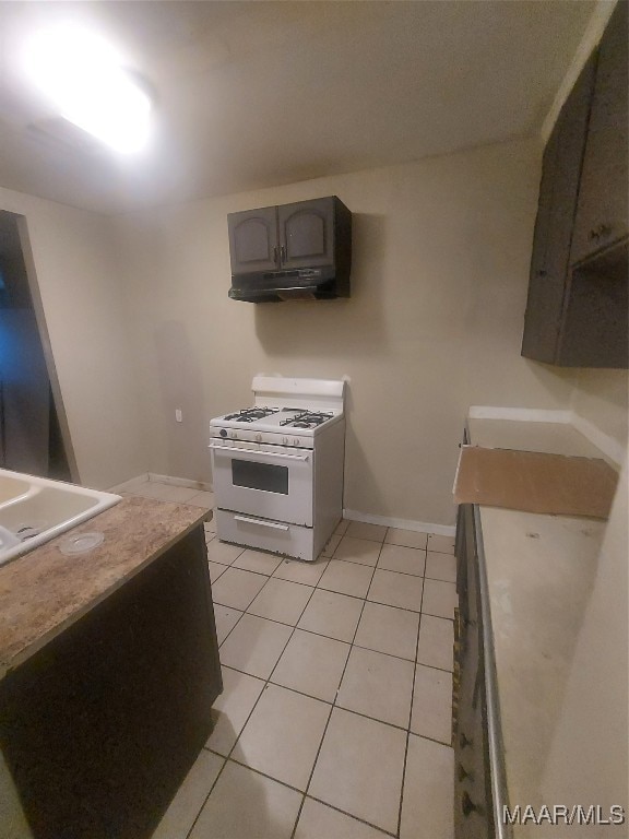 kitchen with sink, white gas range oven, and light tile patterned floors