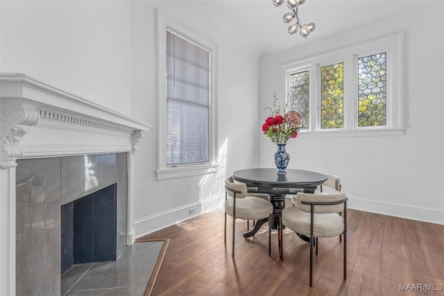 dining space featuring a premium fireplace, baseboards, and wood-type flooring