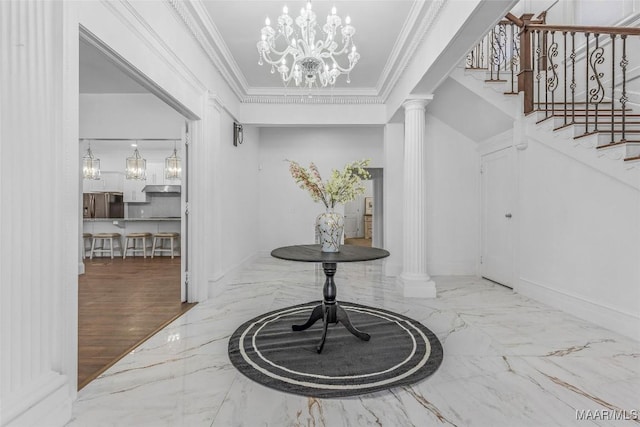foyer featuring decorative columns, marble finish floor, a notable chandelier, and crown molding
