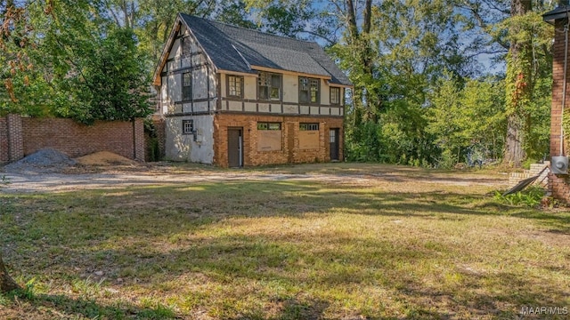 rear view of house featuring a lawn, brick siding, and a shingled roof
