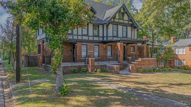 tudor house with brick siding, a shingled roof, and a front lawn