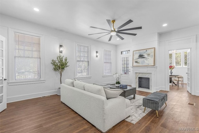 living area with a high end fireplace, wood finished floors, visible vents, and ceiling fan