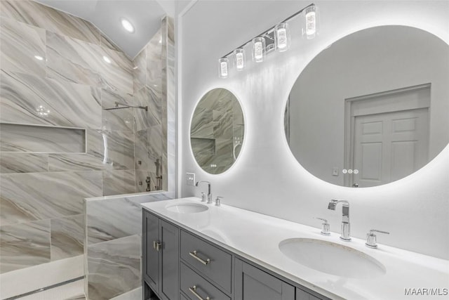 bathroom featuring double vanity, a marble finish shower, and a sink