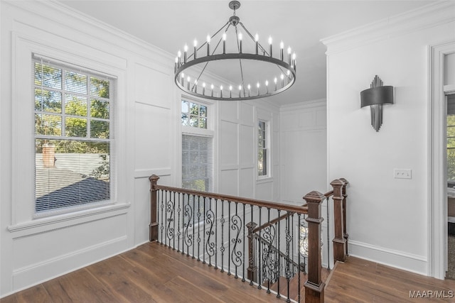 stairs featuring ornamental molding, a notable chandelier, and hardwood / wood-style floors