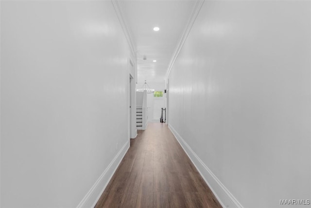 corridor featuring a chandelier, dark wood finished floors, baseboards, ornamental molding, and recessed lighting