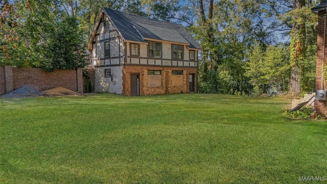 back of house featuring brick siding, a yard, and a shingled roof