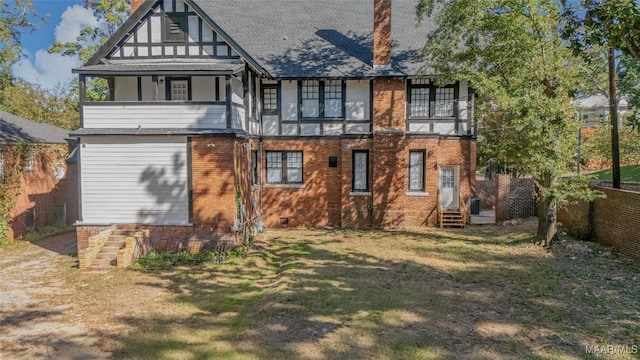 rear view of property with brick siding, a chimney, a balcony, and fence