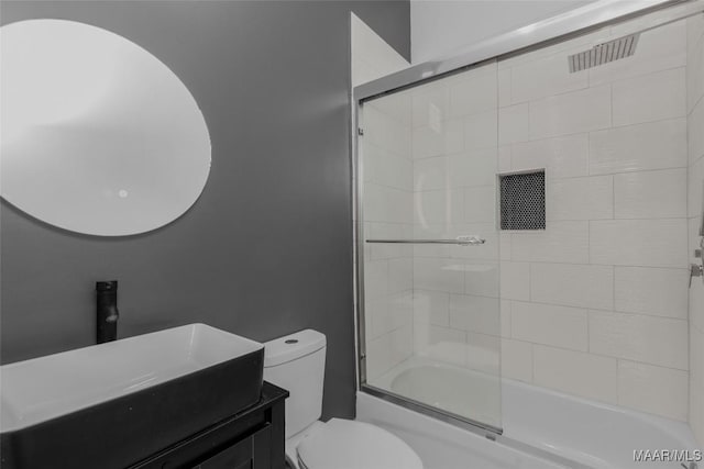 bathroom featuring enclosed tub / shower combo, toilet, and vanity