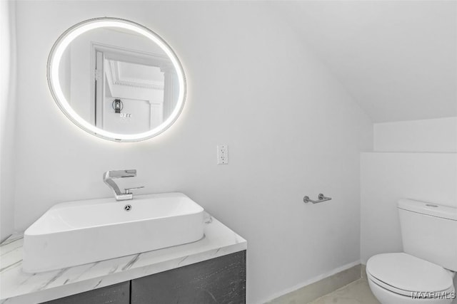 bathroom with lofted ceiling, a sink, and toilet