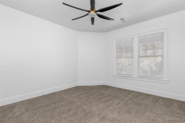 carpeted spare room with baseboards, visible vents, and ceiling fan