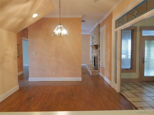 unfurnished dining area with crown molding, a fireplace, wood-type flooring, and an inviting chandelier