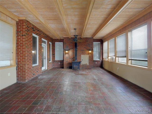 unfurnished sunroom featuring a wood stove, beamed ceiling, and wooden ceiling