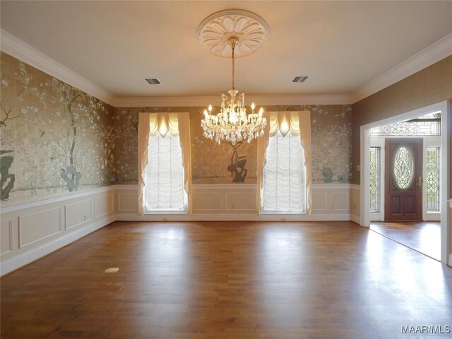 unfurnished dining area featuring visible vents, a chandelier, wallpapered walls, and wainscoting