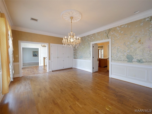 unfurnished dining area featuring ornamental molding, a chandelier, and wood-type flooring