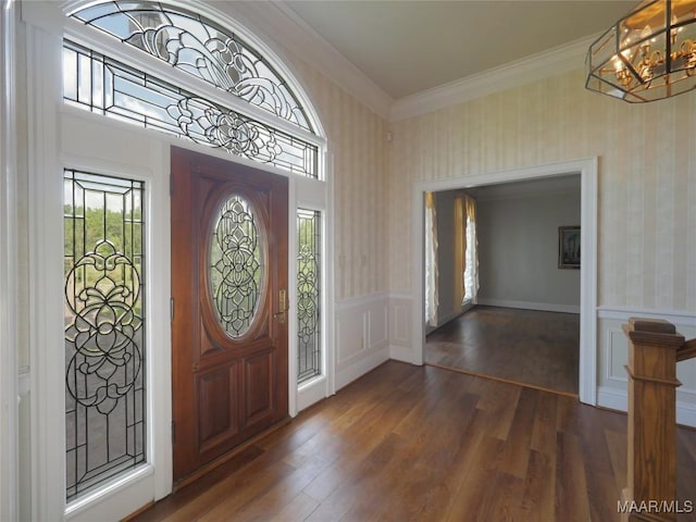 entrance foyer featuring a notable chandelier, wallpapered walls, dark wood-style flooring, wainscoting, and crown molding