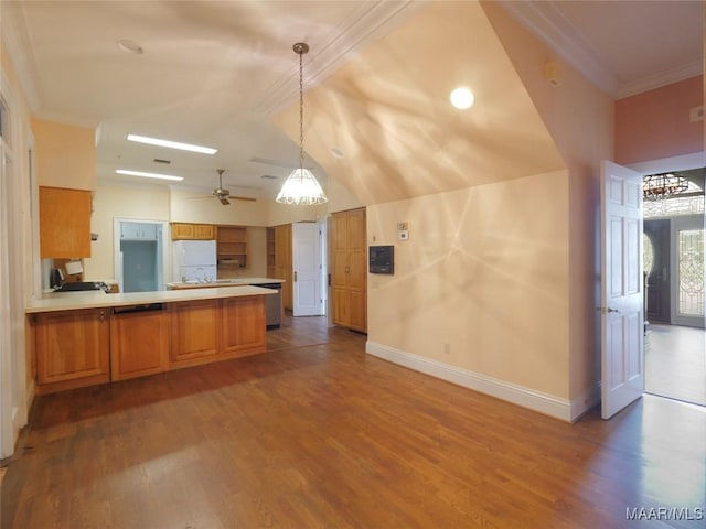 kitchen featuring a peninsula, brown cabinetry, freestanding refrigerator, crown molding, and baseboards
