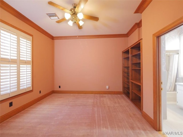 spare room with ceiling fan, visible vents, crown molding, and light colored carpet