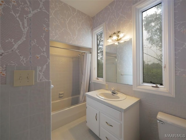 bathroom featuring vanity, toilet, shower / bath combo with shower curtain, and wallpapered walls