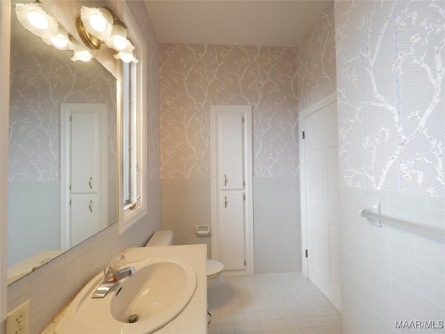 bathroom featuring toilet, tile patterned floors, vanity, and wallpapered walls
