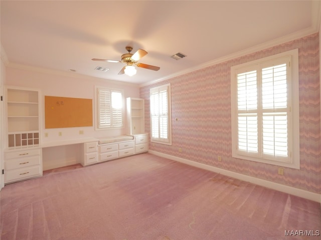 unfurnished room with light carpet, ornamental molding, built in desk, and ceiling fan