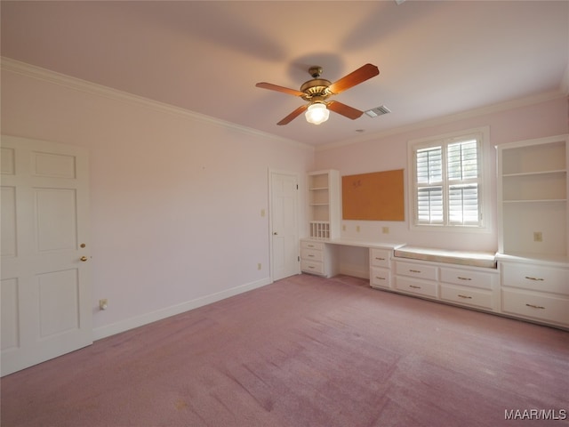 unfurnished bedroom featuring ornamental molding, built in desk, light colored carpet, and ceiling fan