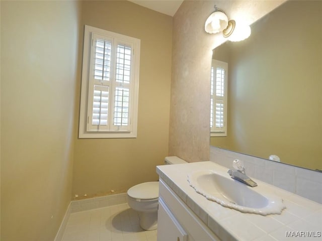 bathroom with toilet, tile patterned flooring, vanity, and baseboards