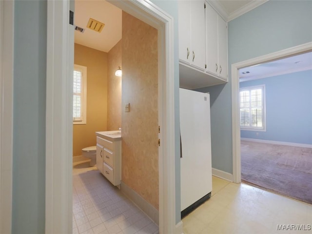 interior space with baseboards, toilet, ornamental molding, tile patterned floors, and vanity