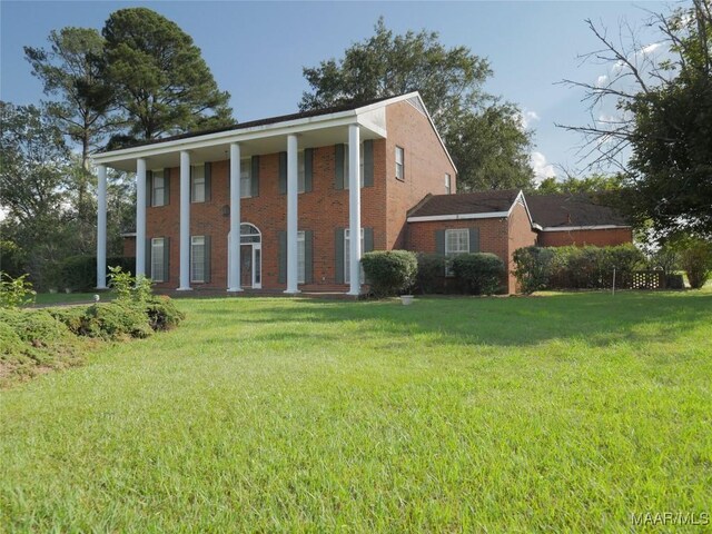 neoclassical home featuring brick siding and a front yard