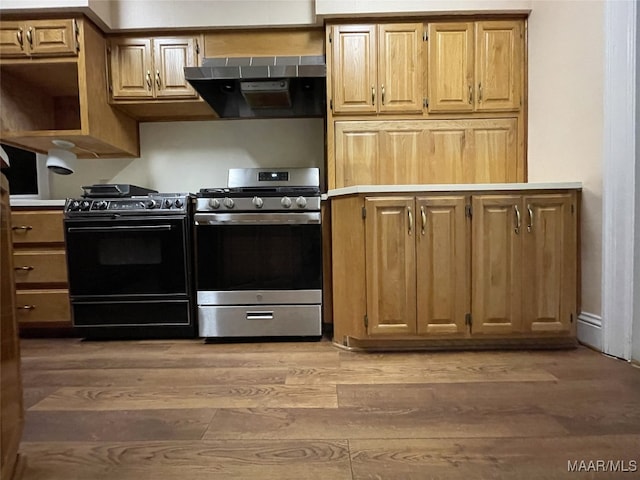 kitchen featuring extractor fan, stainless steel range with gas cooktop, black range with electric stovetop, and light wood-type flooring