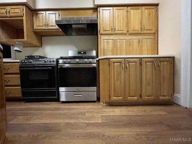 kitchen with extractor fan, light wood-type flooring, gas stove, light countertops, and black stove