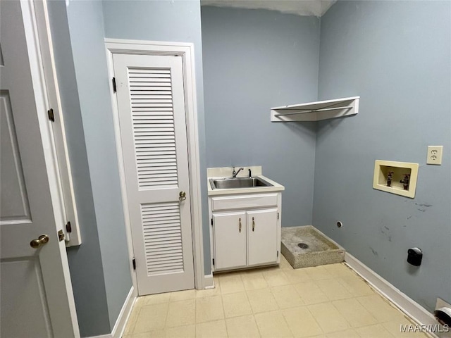 washroom with a sink, washer hookup, cabinet space, and baseboards