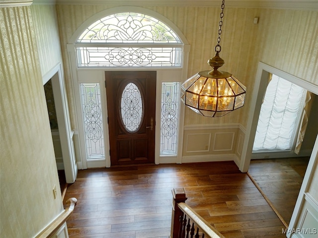 foyer featuring an inviting chandelier, plenty of natural light, and dark hardwood / wood-style floors