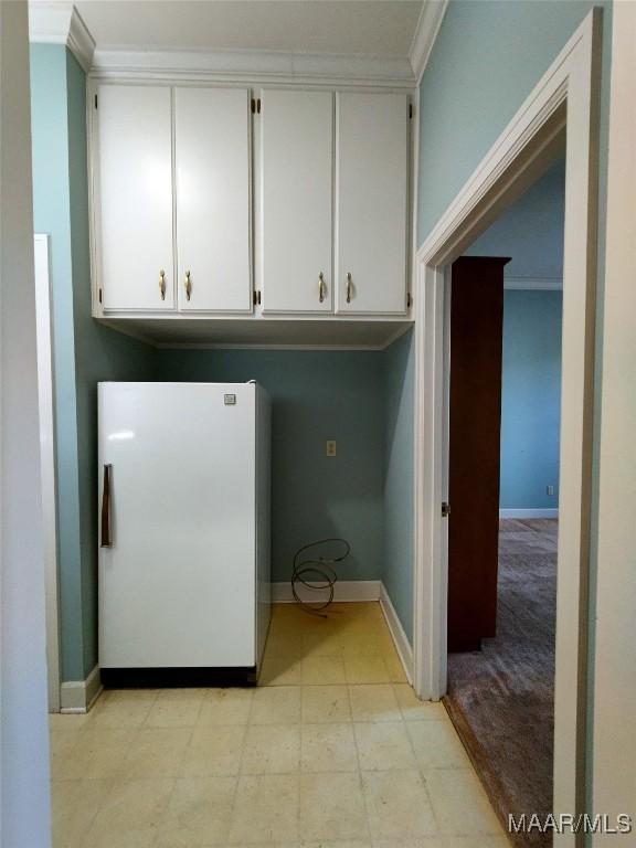 laundry room featuring crown molding, light floors, and baseboards
