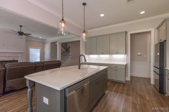 kitchen featuring dark wood-type flooring, gray cabinetry, stainless steel appliances, a center island with sink, and sink