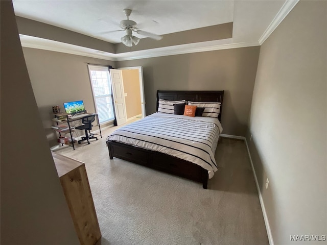 carpeted bedroom with crown molding, a tray ceiling, and ceiling fan