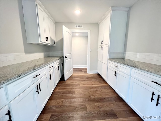 kitchen with white cabinetry, light stone counters, and dark wood-type flooring