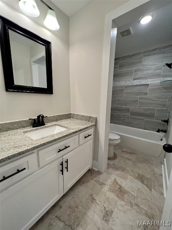 full bathroom featuring vanity, tiled shower / bath combo, and toilet