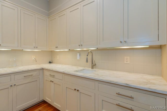 kitchen featuring white cabinetry, light stone countertops, and sink