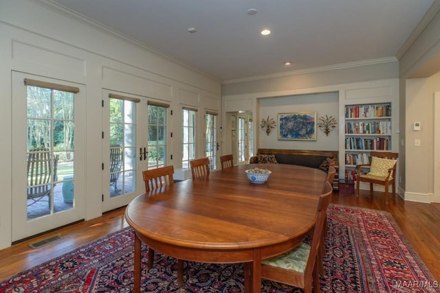 dining room featuring crown molding, dark wood-type flooring, built in features, and french doors